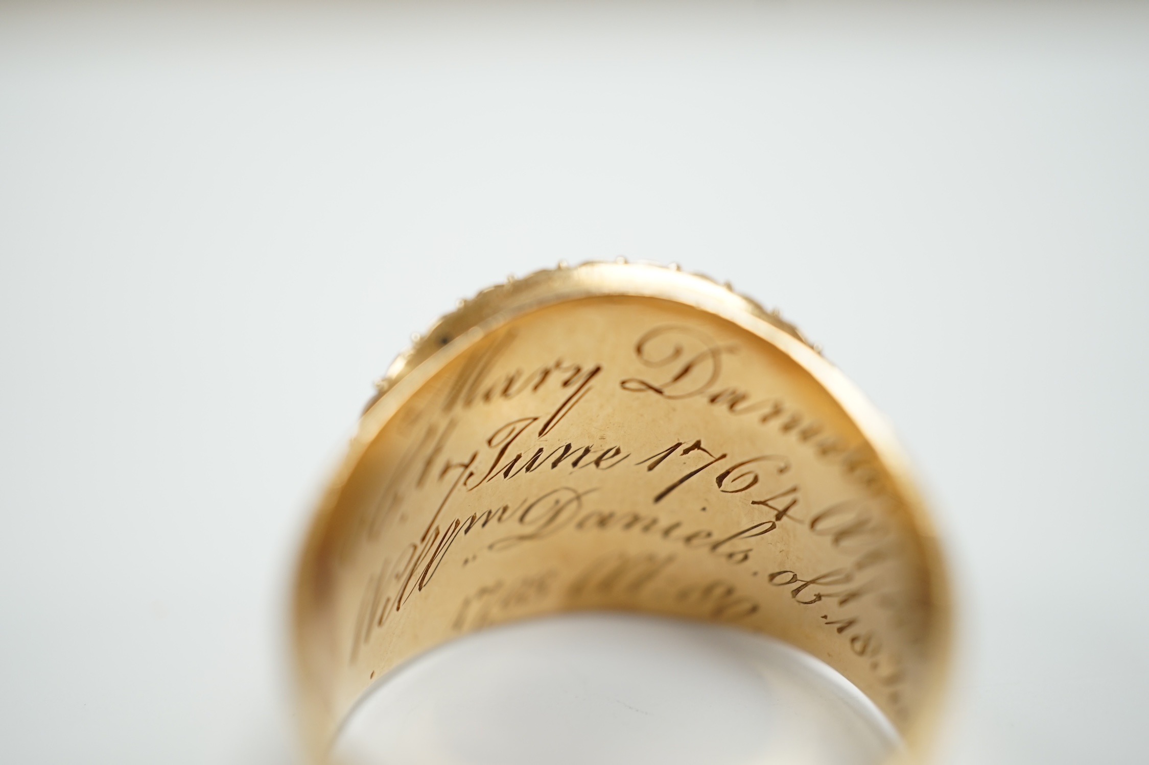 A George III yellow metal, enamel and split pearl set mourning ring, with central glazed panel and engraved inscription, 'Mary Daniels Obt. June, 1764 at 40 Willm Daniels obt 18 June, 1793 at 80', size R, gross weight 7.